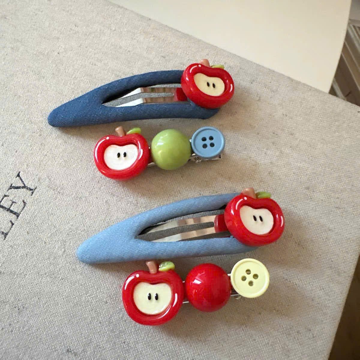 Kẹp tóc bọc vải xanh dương charm tim nơ táo đỏ